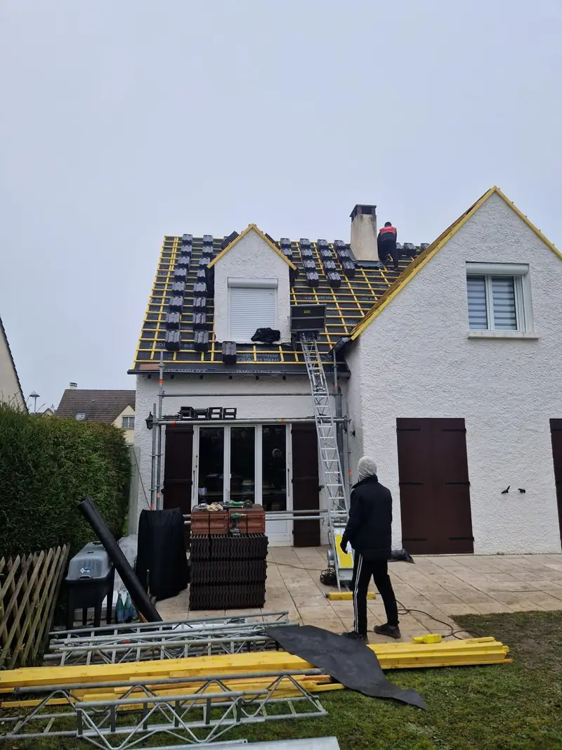 Maison sous échafaudage pendant la pose de tuiles brunes neuves par Les Toitures de Kevin, couvreur en Essonne
