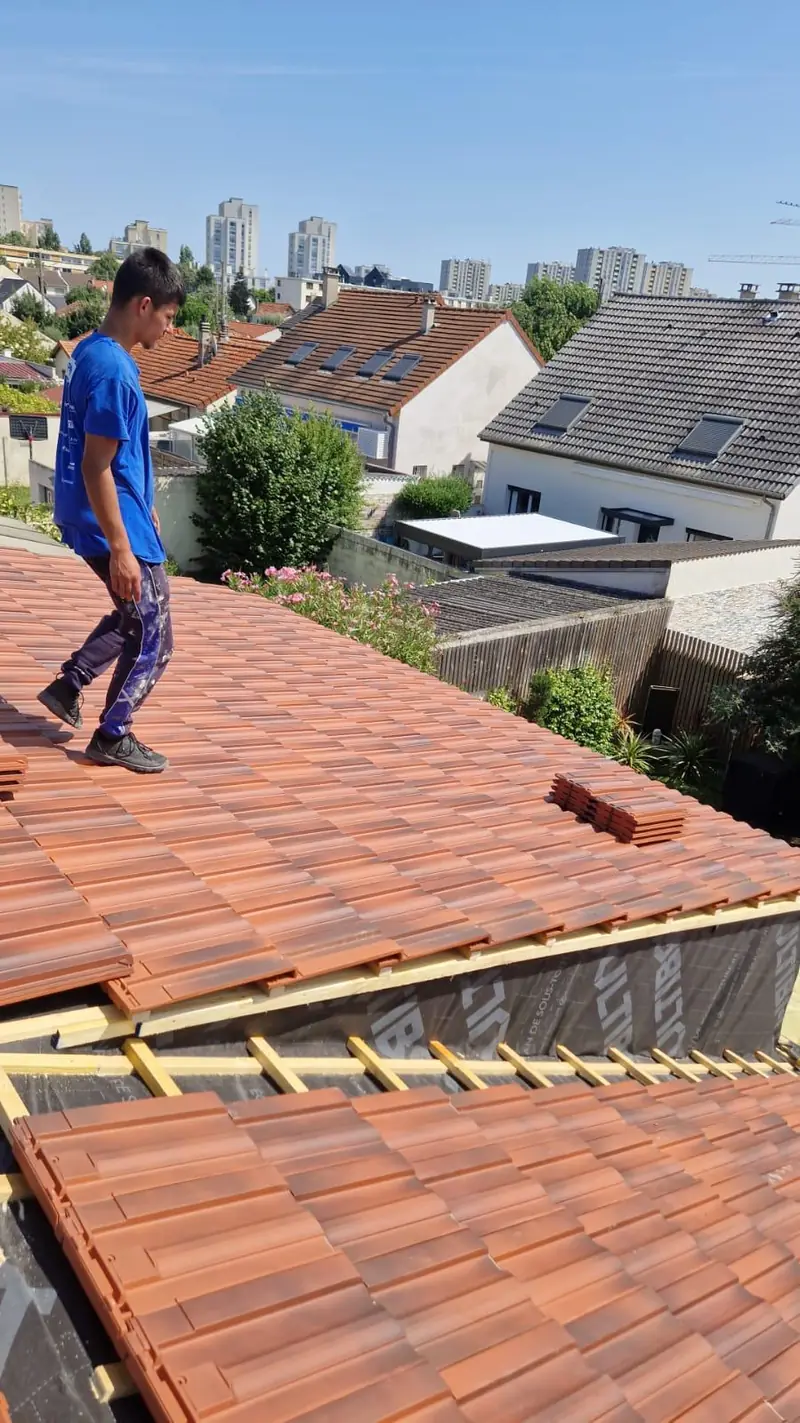 Couvreur sur une toiture en cours de pose de tuiles terre cuite par Les Toitures de Kevin, couvreur en Essonne