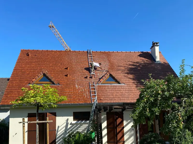 Couvreur nettoyant une toiture en tuiles terre cuite au nettoyeur haute pression par Les Toitures de Kevin, couvreur en Essonne