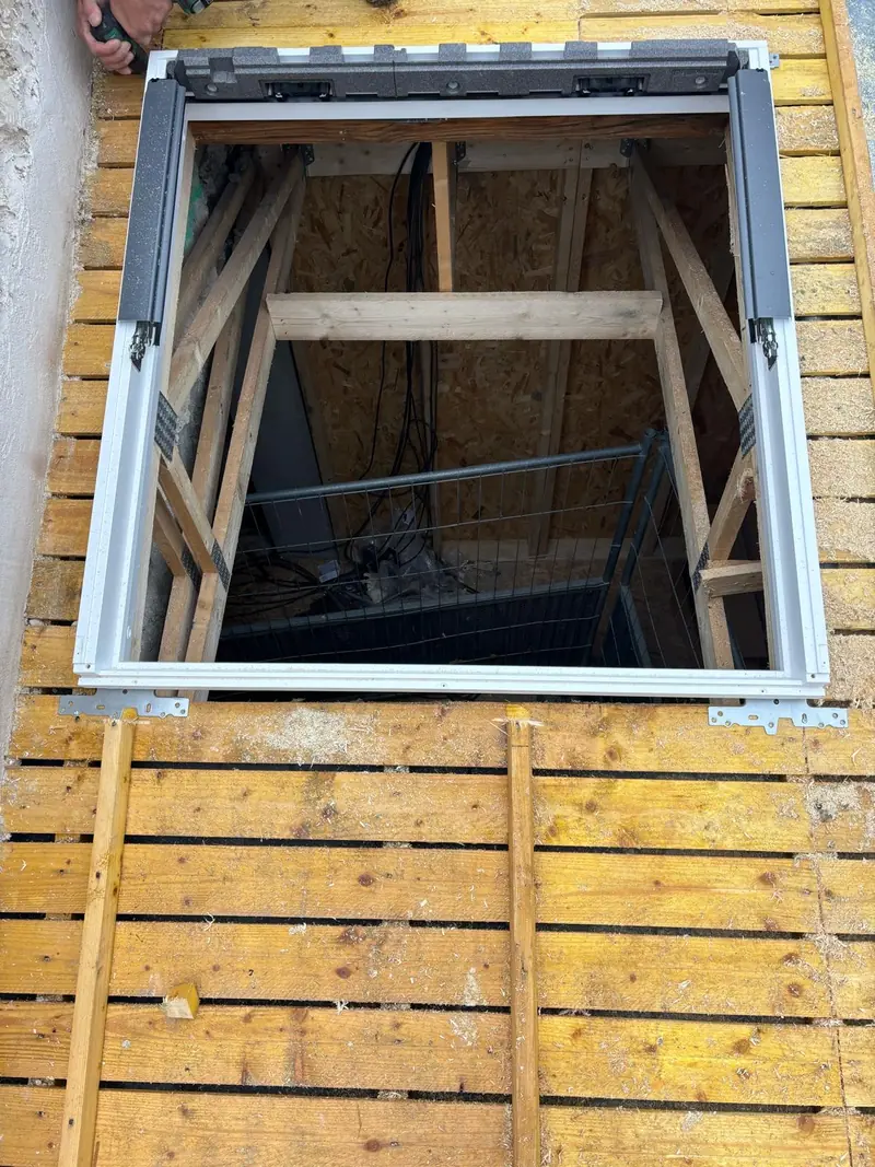Dormant de fenêtre de toit sans ouvrant, fixé sur le support bois de la toiture ; la charpente se voit par l'ouverture